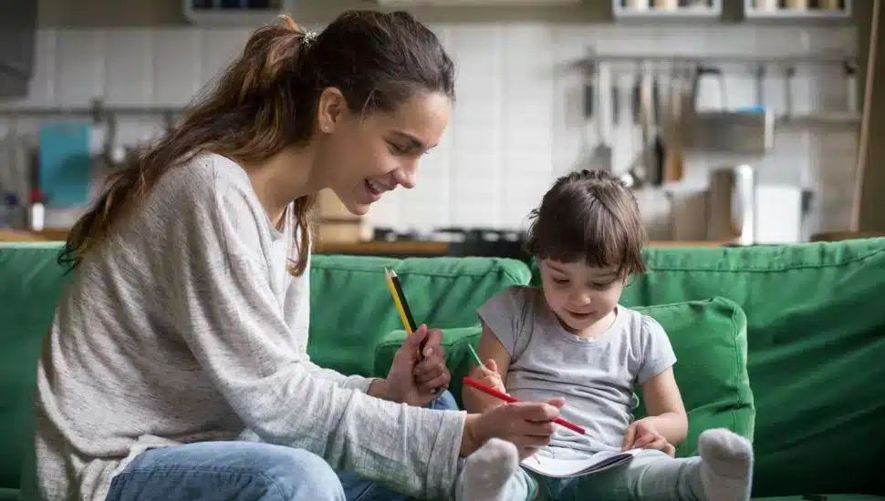 A mom and child drawing on couch.