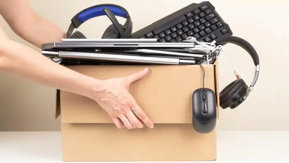 A person packing up electronics in a box.