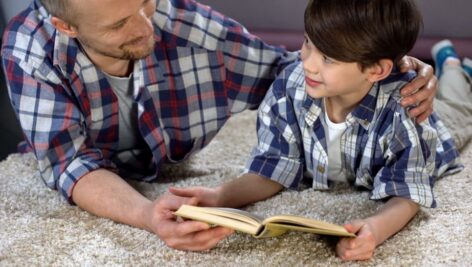 A father has some quality time with his son reading a book.