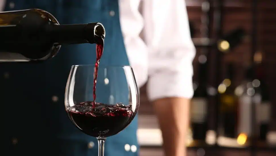 A bartender pouring wine into a glass.