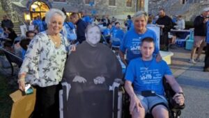At a pilgrimage in honor of Father Bill Atkinson held in September, are, from left, Mary Moody with a cardboard cutout of Atkinson and Marie Keith with her son Cole.