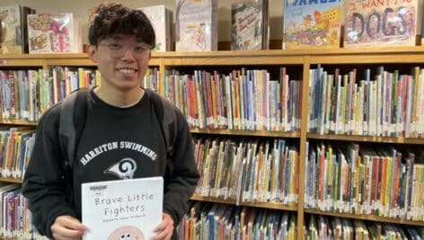 Ethan Niu holding his book, "Brave Little Fighters."