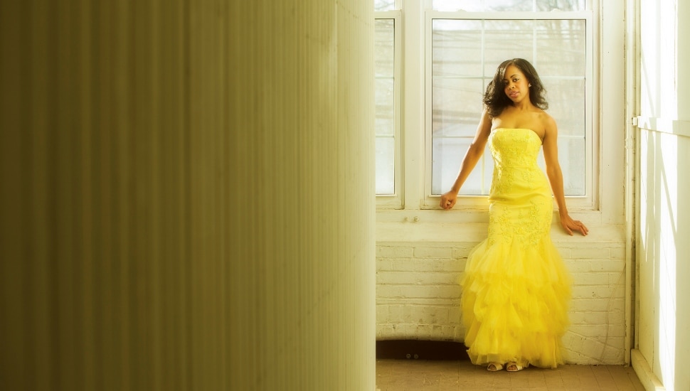 Girl in a window wearing a prom dress
