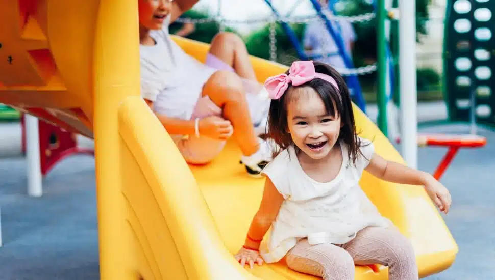 A little girl at the bottom of a slide.