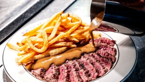A plate of medium rare steak and French fries.