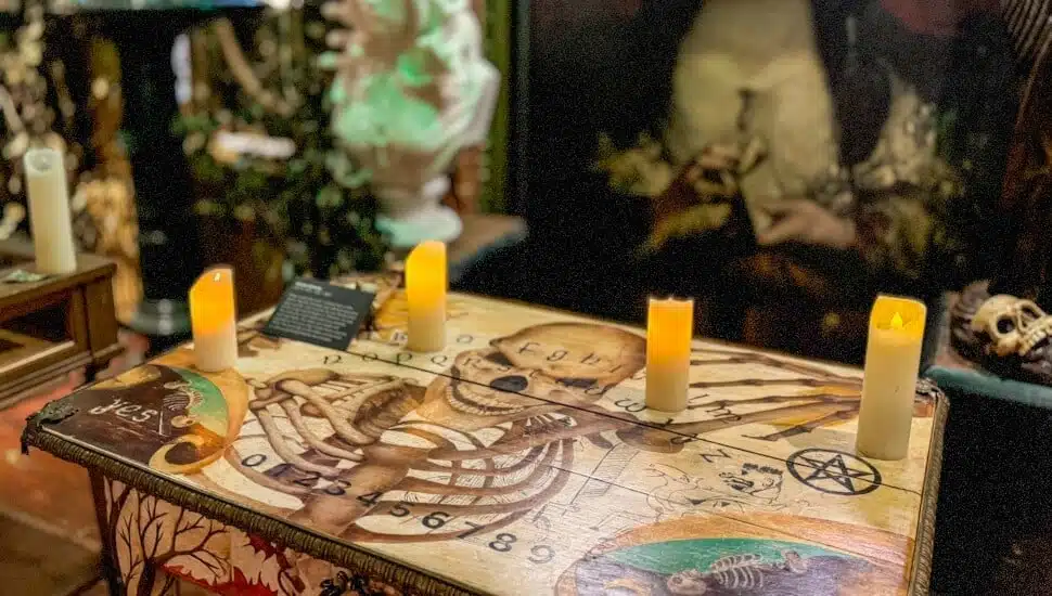 Candles on top of a talking board table with a painting in the background at Vampa.