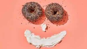 Bagels and cream cheese formed in the shape of a smiling face.