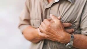 A man holding his chest, experiencing chest pain.