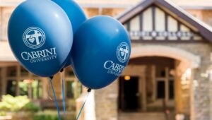 Balloons with the Cabrini University name and logo tethered to a building on campus.