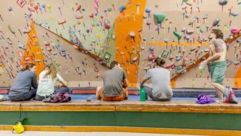 Young people sitting by rock wall at Philadelphia Rock Gyms.