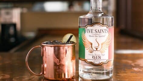 A whiskey bottle and a metal cup at Five Saints Distillery.