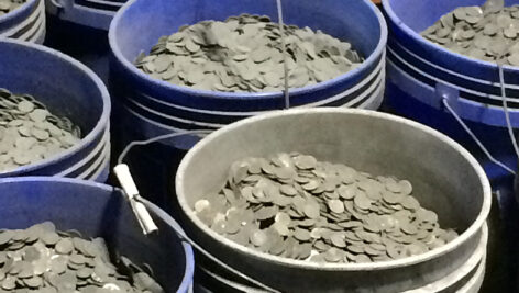 sooty coins in blue buckets await processing.