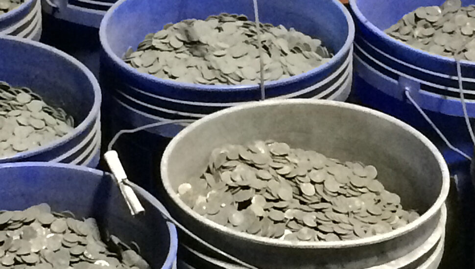 sooty coins in blue buckets await processing.