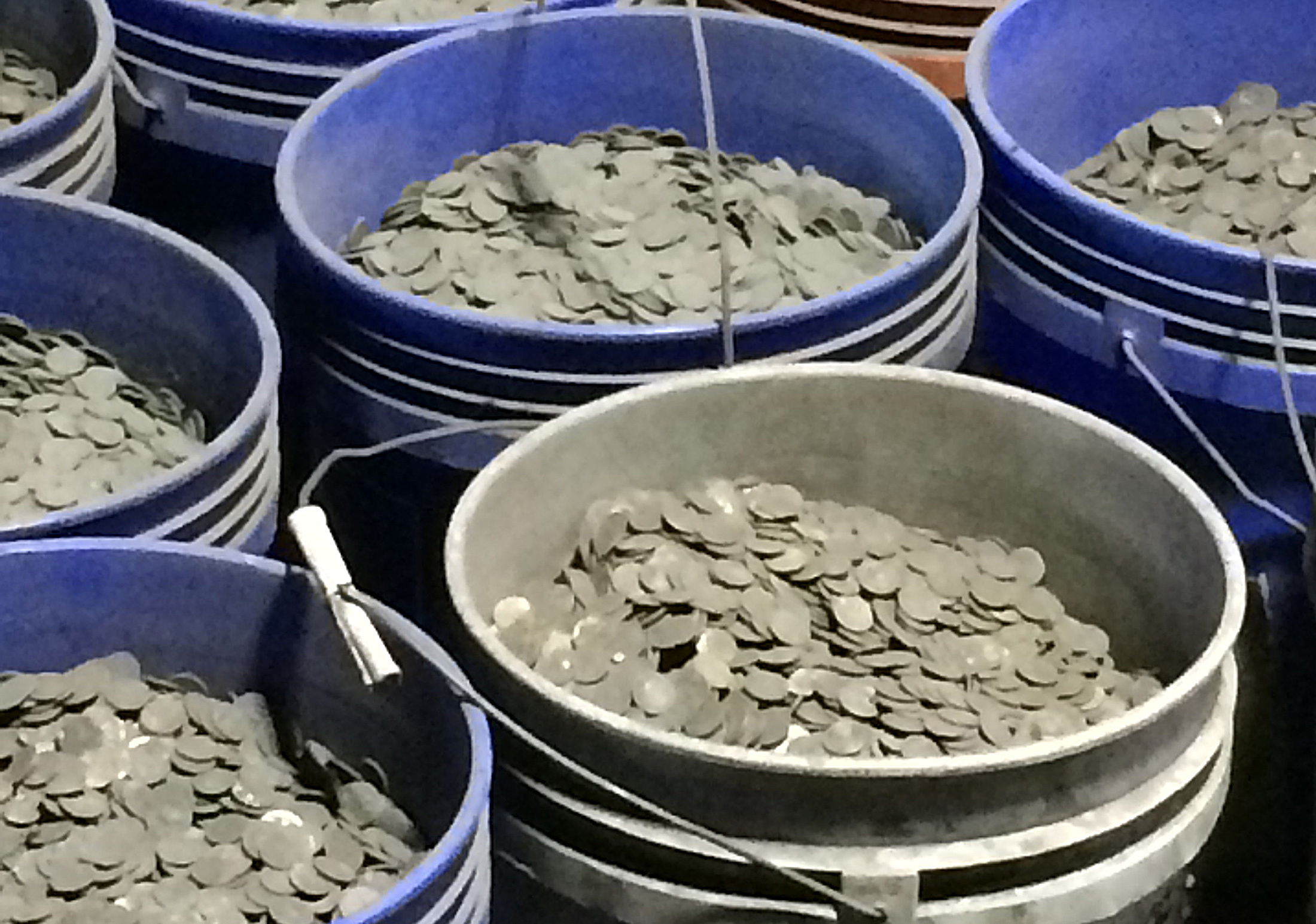 sooty coins in blue buckets await processing.