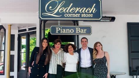 Owners of Ledarch corner store in front of sign