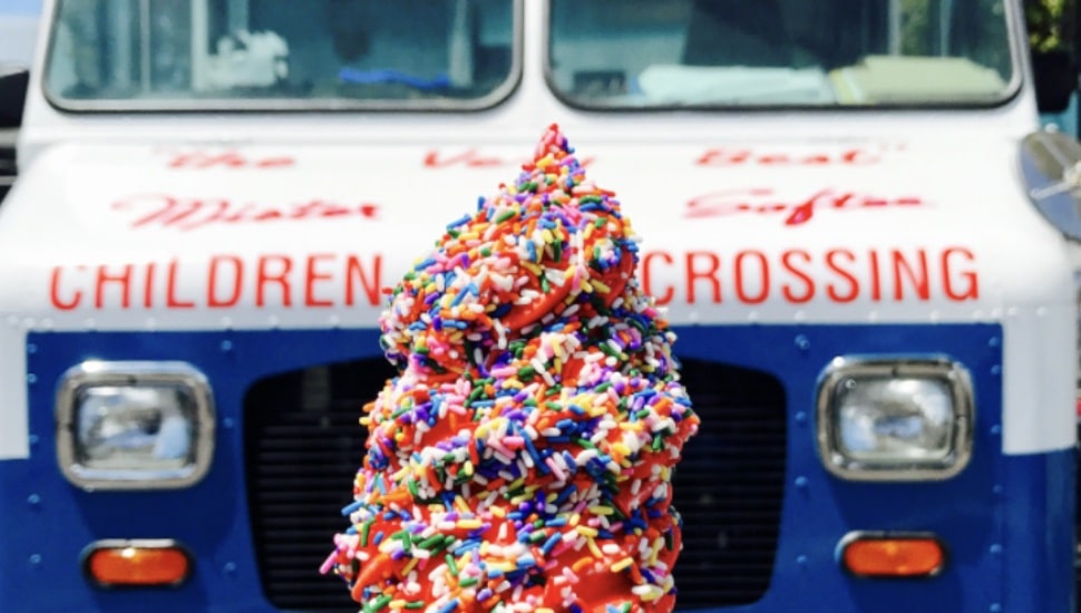 Soft serve ice cream with rainbow sprinkles superimposed over ice cream truck