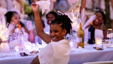 Woman at Fete en Blanc waving a white napkin over her shoulder.