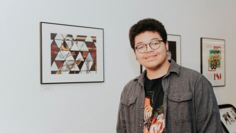 Harcum College Graphic Design student Eidan Ortiz ‘24 presents his work at the annual student exhibition.