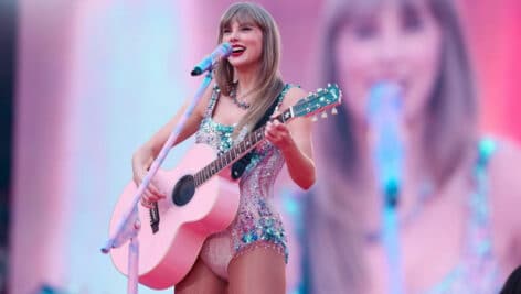 Taylor Swift performing while playing a guitar.