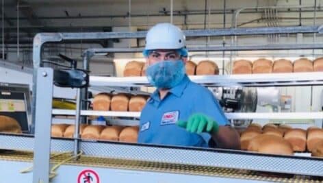 A masked factory worker at a factory assembly line for Bimbo Bakeries.