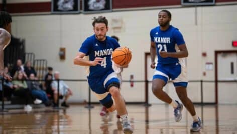 Eddie Fortescue on basketball court next to teammate, dribbling basketball