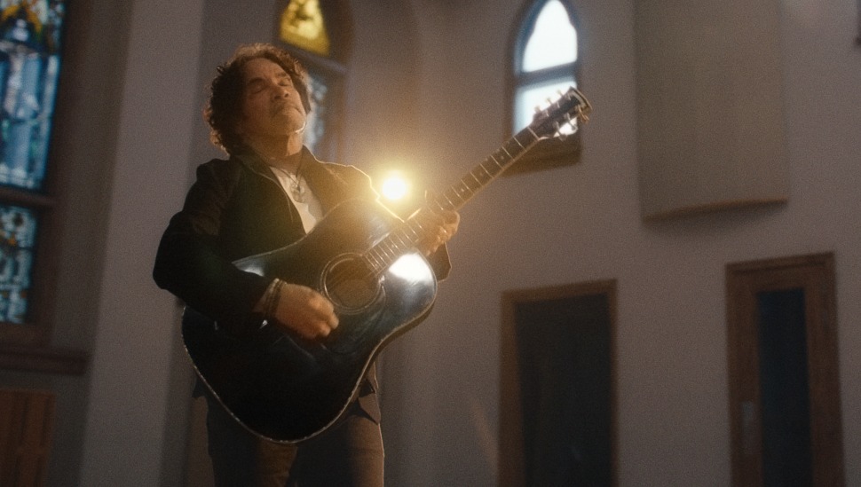 John Oates singing and playing a guitar.