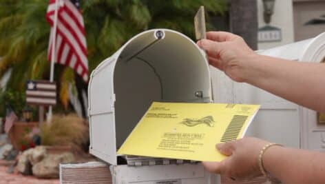 Close up of an American mailbox with flags in the background.