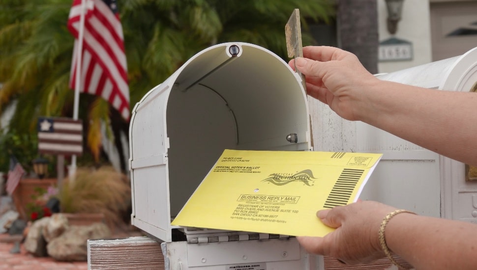 Close up of an American mailbox with flags in the background.