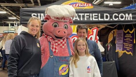 The Hatfield mascot Smiley has his picture taken with two girls at the Pennsylvania Farm Show.