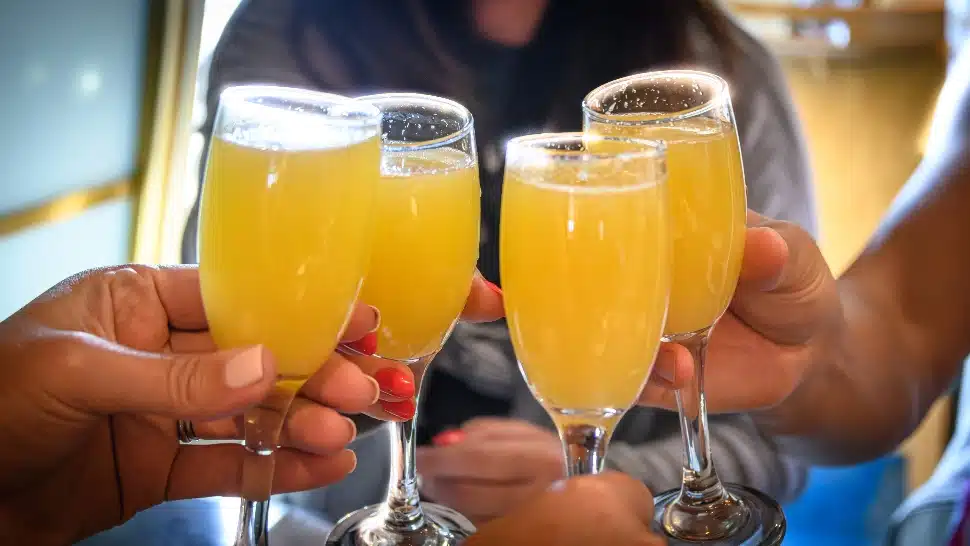 four people hoist a memosa toast.