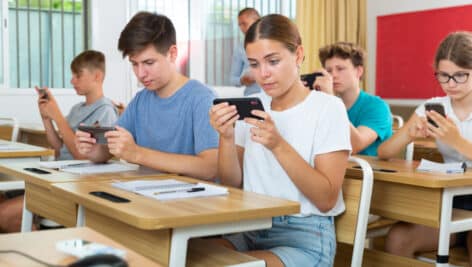 Students in a classroom using their cell phones.