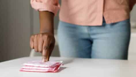 Young african american woman taking disposable menstrual pad from table