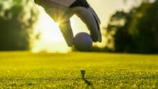 Man placing a golf ball on a tee