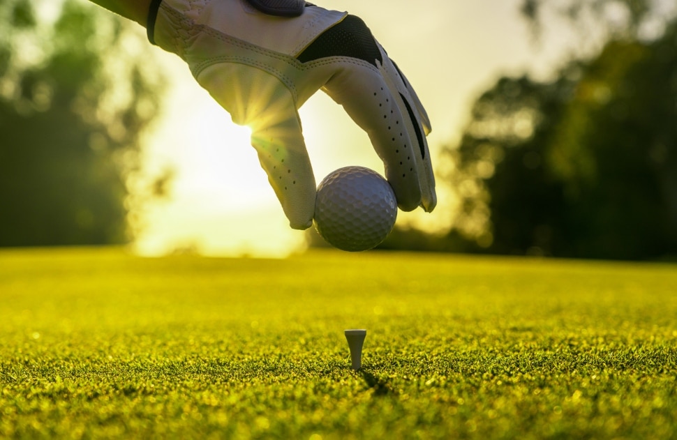 Man placing a golf ball on a tee