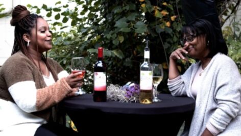 Two women sitting at a table enjoying wine from C;yrenity Sips Winery.