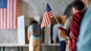 A voter holds an American Flag as she waits in line to vote.