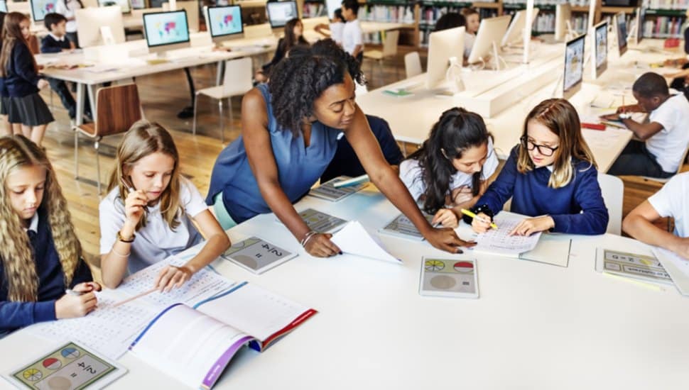 A teacher works with young students on a school project.