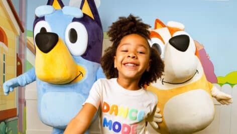 Young girl poses with Bluey and Bingo at the Camp Interactive Experience