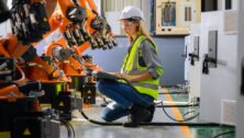 Worker checking parts of robotic machine.