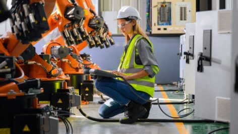 Worker checking parts of robotic machine.