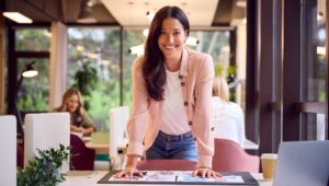 A Businesswoman At Table In Office Checking Design Layouts.