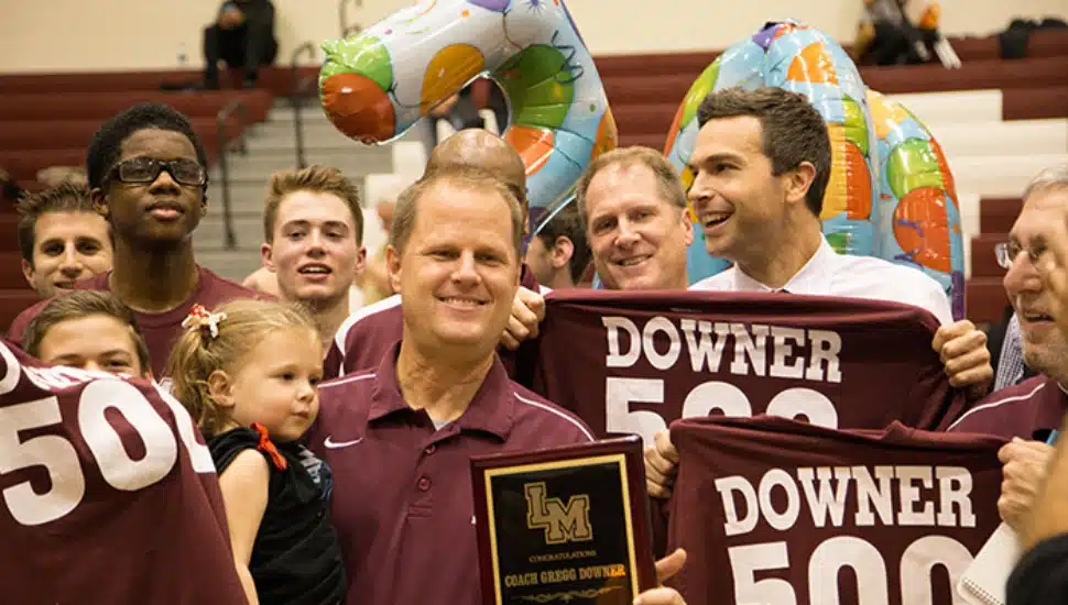 Lower Merion High School Boys Basketball coach Gregg Downer posing with his team.