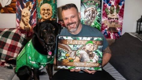 Jon Metz posing with his artwork and his dog.