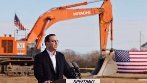 Governor Josh Shapiro addresses a crowd in front of a developing site.