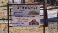 A roadside sign advertising Redeemer Valley Farm Farmer's Market