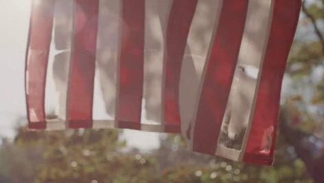 A tattered U.S. flag hanging on a porch.