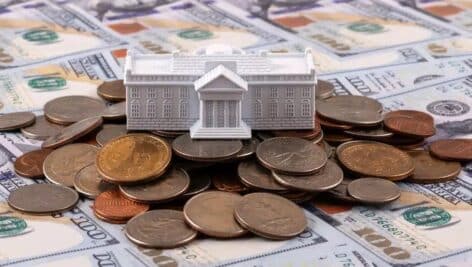 A White House figurine atop a pile of money.