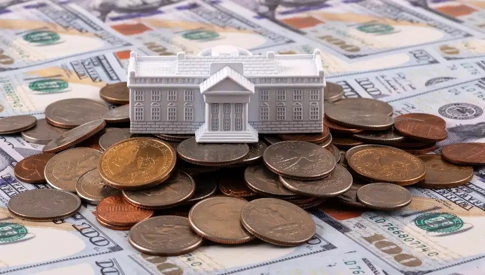 A White House figurine atop a pile of money.