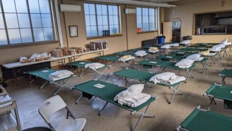 A code Blue Shelter with cots and pillows in a room.