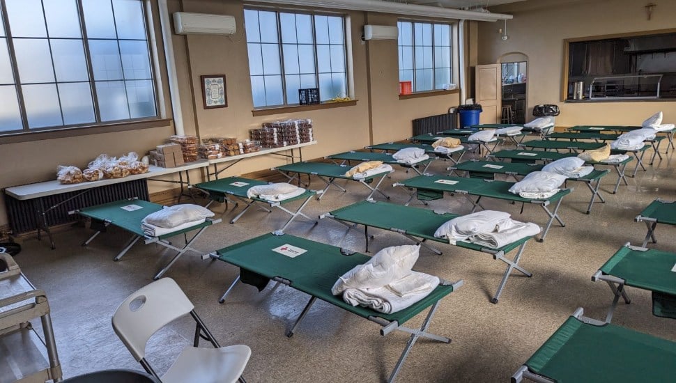 A code Blue Shelter with cots and pillows in a room.